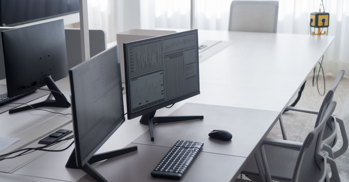 Escritorio regulable en altura con silla y monitor en un cuarto de trabajo