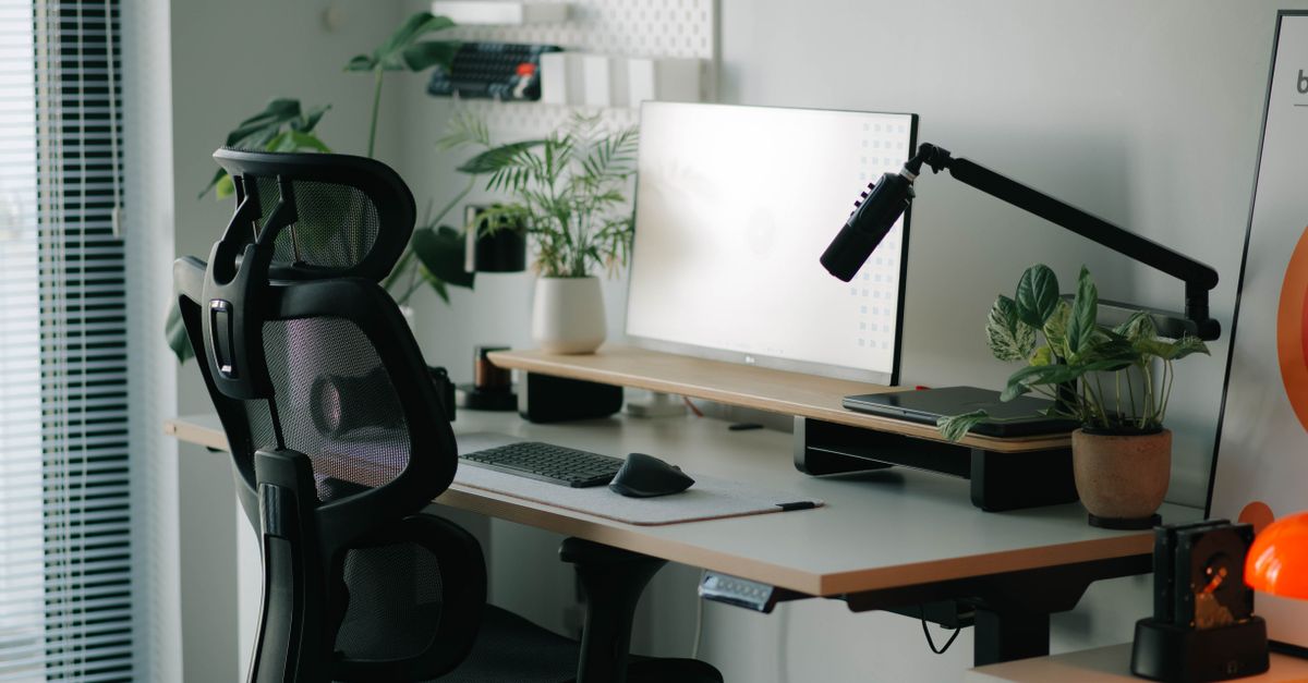 Silla de oficina frente a un escritorio de madera con monitor y teclado