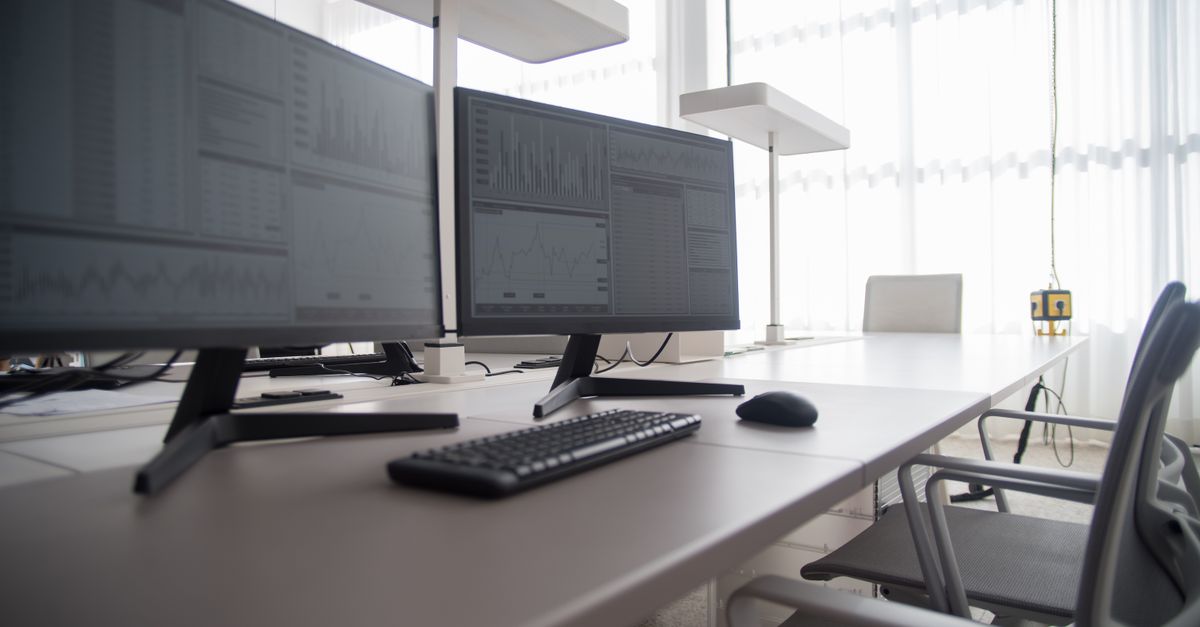 Escritorio regulable en altura con silla y monitor en un cuarto de trabajo