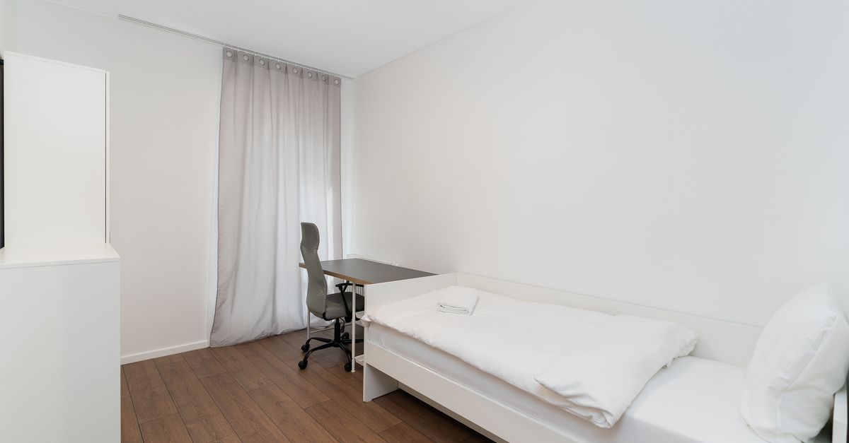 Escritorio regulable junto a una silla de oficina en un ambiente pequeño