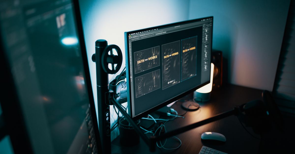 Monitor de escritorio encendido junto a teclado y cuaderno sobre una mesa